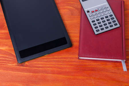 Black tablet, calculator and notebook on the tableの写真素材