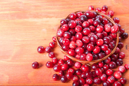 Fresh cranberries in a small basket on a wooden backgroundの写真素材