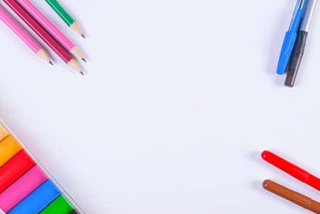 School supplies - pens, pencils, clay and crayons on a sheet of white paperの写真素材