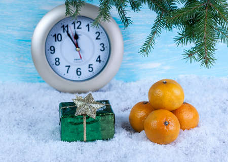 Background with a gift box and tangerines on snow and a clock.の写真素材