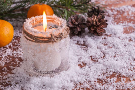 New Year composition with a burning candle, tangerines and fir branches on a wooden backgroundの写真素材
