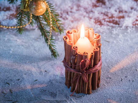 Burning candle in a homemade candlestick standing on a wooden surface. の写真素材