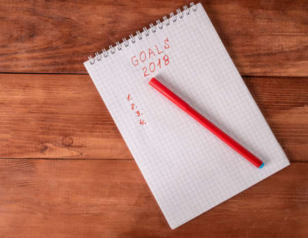 Notepad with goals and a red pencil on a New Year's backgroundの写真素材