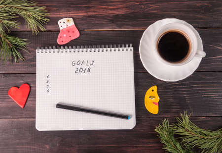 Notepad with notes, coffee mug and Christmas tree decorations on a dark tableの写真素材