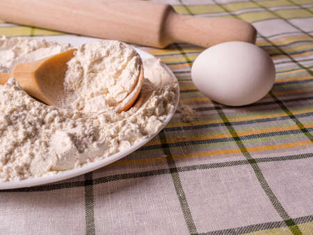 Culinary background - flour, eggs and a wooden rolling pin on the tableの写真素材