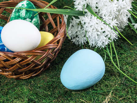 Wooden basket with Easter eggs on the grass field.の写真素材