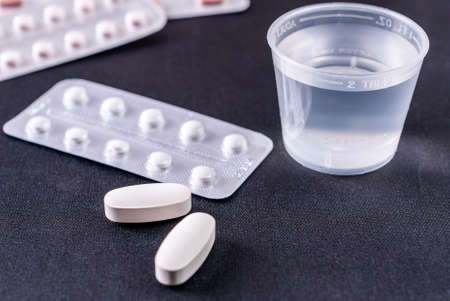 Tablets and plastic glass with water on a black backgroundの写真素材