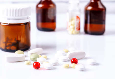 Tablets and medical bottles on a white table.の写真素材