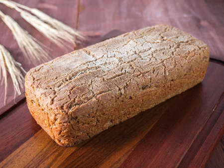 Homemade baked bread and a stalk of wheat on a cutting board