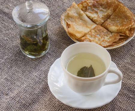 Pancakes and a cup of Chinese green tea on a tableclothの写真素材