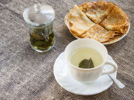 Pancakes and a cup of Chinese green tea on a tableclothの写真素材