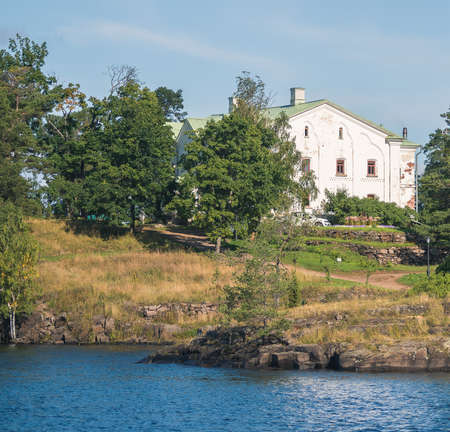 A white house next to a stone beach because of trees.の写真素材