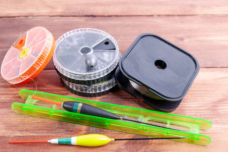 Float with fishing line, round boxes for small gear on a wooden backgroundの写真素材