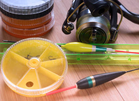 Spinning reel, spare coil with a fishing line and a round yellow box with small accessories on a dark wooden backgroundの写真素材