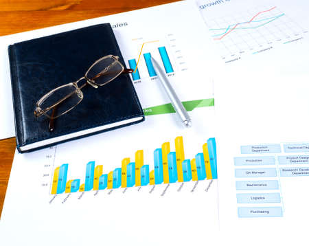 Desktop with graphic chart diary and glasses and pen