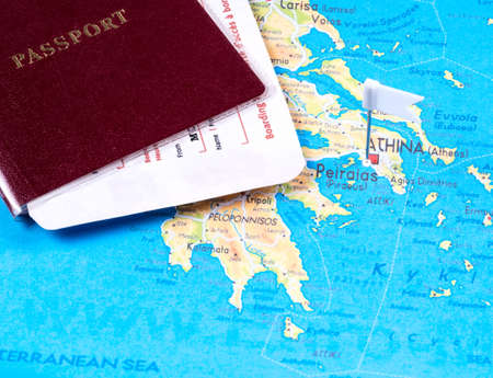 Red passport with attached boarding passes on a map of Greeceの写真素材
