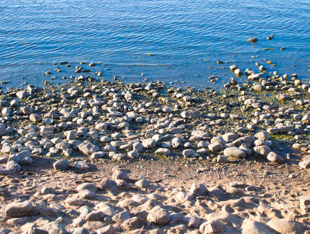 the river bank, the sea covered with pebbles. stone shore and waterの写真素材