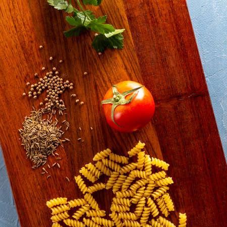 Ingredients for cooking food on the kitchen board. Tomatoes, Basil, Pasta and Spicesの写真素材