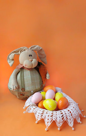Easter bunny and easter eggs in basket on orange background.の写真素材