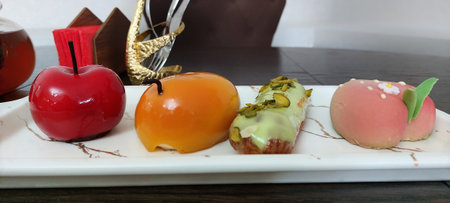 Tasty cakes on a white plate with a red apple in the backgroundの写真素材