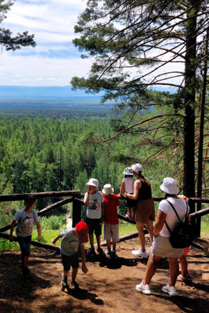 Tourists looking at the view from the top of the mountain in the forest.Women and children.の写真素材
