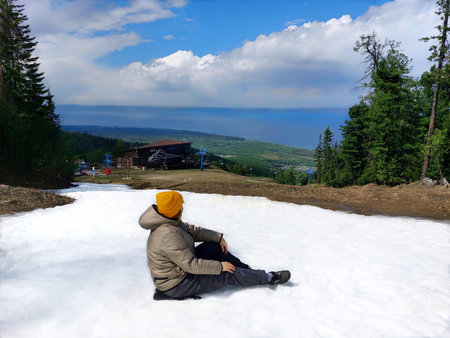 Hiker sitting on the snow and looking at the sea in the mountainsの写真素材