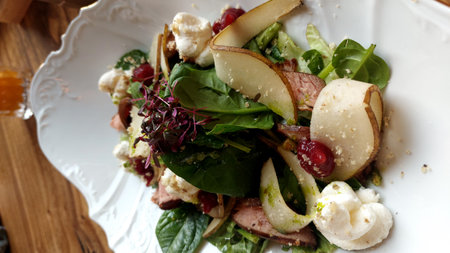 Delicious salad with pear, duck fillet,cheese and cranberries on white plateの写真素材