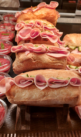 Baguette with ham and cucumber on display in a shopの写真素材