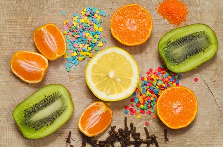 Half a lemon, kiwi, tangerines and spices, lying on a texture surface of an old tree.