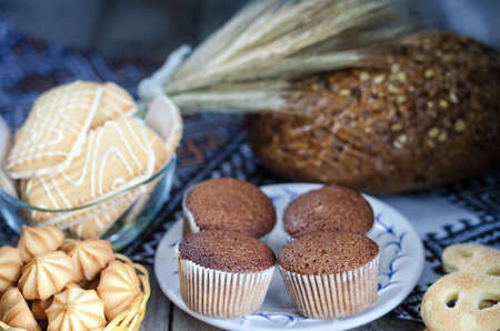 Various kinds of bread and rye ears on the old Board and a towel, rustic style, bokehの写真素材