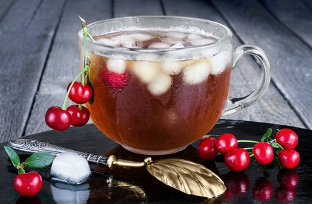Iced tea with berries and ice, vintage spoon and gray background of boardsの写真素材