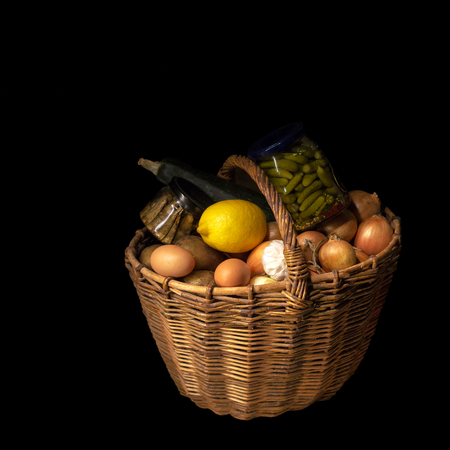 Old, rustic basket, on a black background filled with productsの写真素材