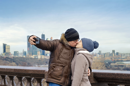 Moscow, Russia-February 07, 2016: the lovers are photographed on the phone in the background of the city and kiss.のeditorial素材
