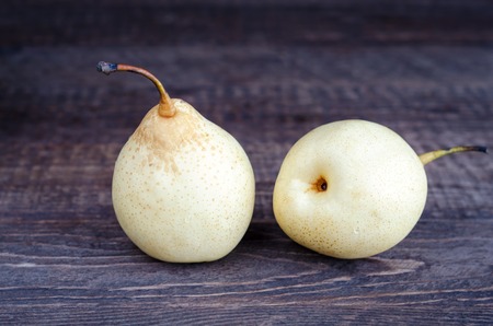 Two yellow pear lying on a wooden surface. Selective focus, low key.の写真素材