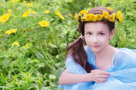 Little girl in wreath of dandelions sitting in the flower meadow. Selective focusの写真素材