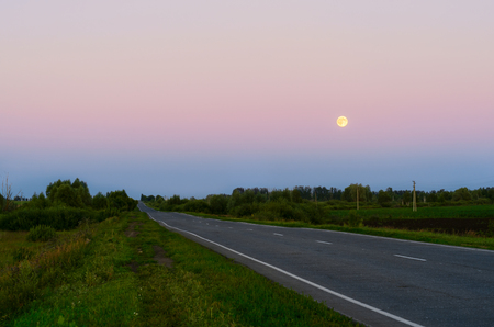 Highway under a full moon, and the sky with the reflection of sunsetの写真素材