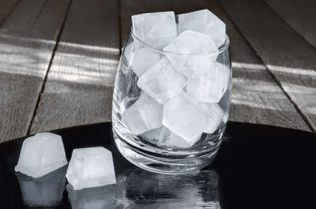 Ice cubes in a glass, gray wood background and the morning light