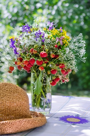 Bouquet of strawberries on the table in the garden in the summerの写真素材