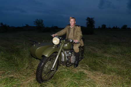 Festival of military history of Russia of XX century . Togliatti, July 7, 2017. Red Army soldier on a motorcycle. Night, artificial light.のeditorial素材