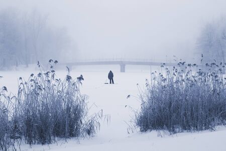 Fog on the winter river. Bridge and fisherman in the distance, stands back.の写真素材