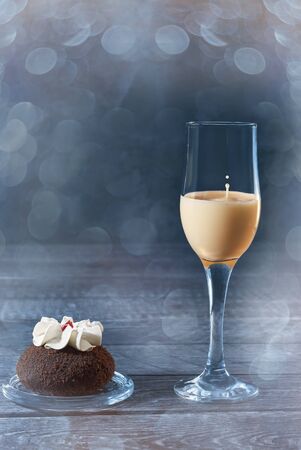 Eggnog cocktail is a hot winter drink with milk, eggs and dark rum in a shot glass on a blue dark...
