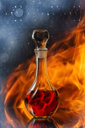 Whiskey in a decanter against a natural flame. Reflection in the glass tabletop. Bokeh overlay