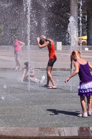 Several little girls play in the spray of the city fountainの写真素材