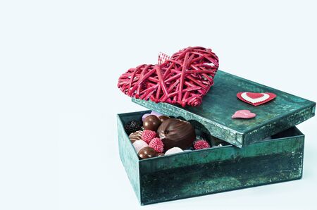 Sweets and decorative heart in an old tin box isolated on a white backgroundの写真素材