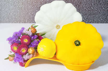 Different squashes and colorful bouquet lying on white kitchen table. Concept of harvesting,...