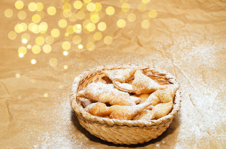 Cookies brushwood, sprinkled with powdered sugar, lies in a basket on crumpled paper. Selective...