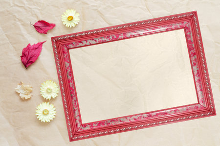 Photo frame with clean paper for text, dried autumn leaves and flowers, on a background of beige...