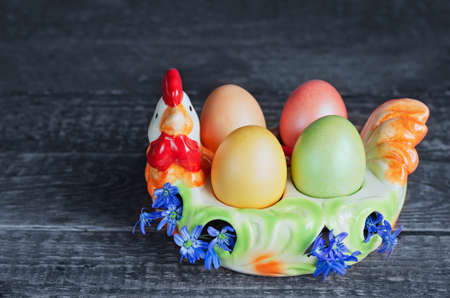Easter eggs on a colorful chicken-shaped plate, on a wooden background