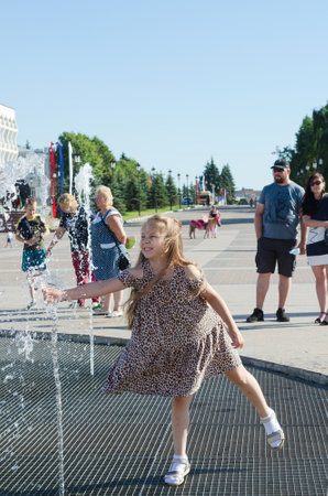 People at the fountain, abnormal heat in Russia. The girl enjoys the cold streams of water. Ulyanovsk, Russia, June 19, 2021のeditorial素材