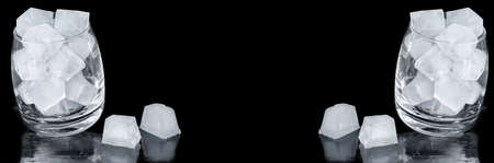 Ice cubes in a glass on a black widescreen background. The concept of making soft drinks, bannerの写真素材